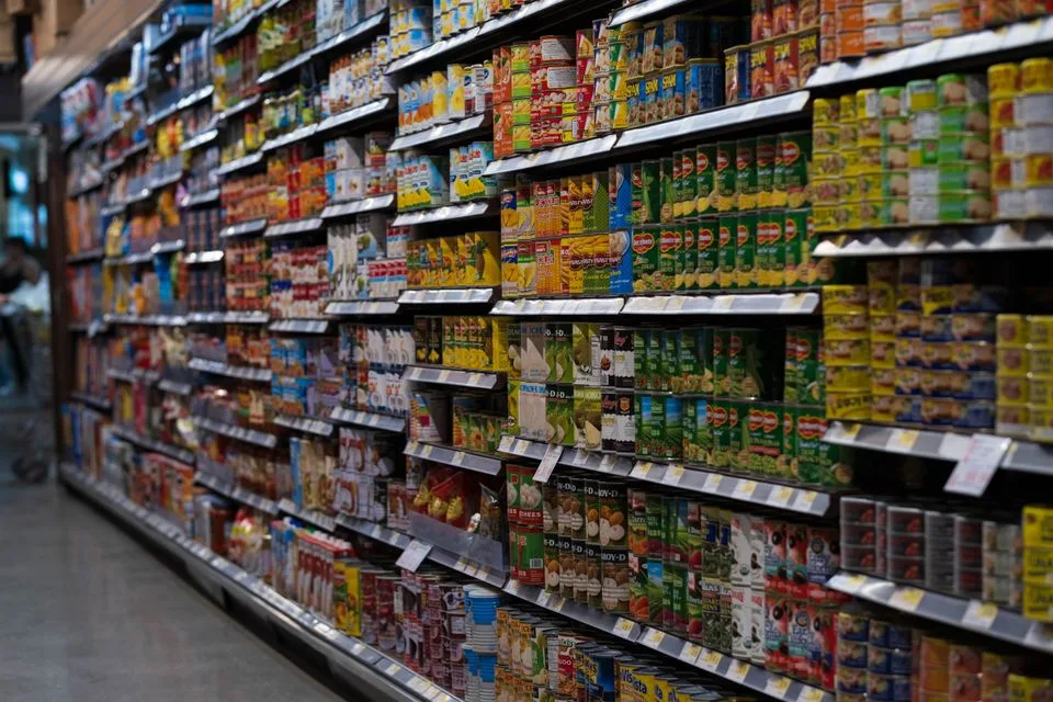 Corredor de supermercado com dezenas de latas parecidas enfileiradas na prateleira