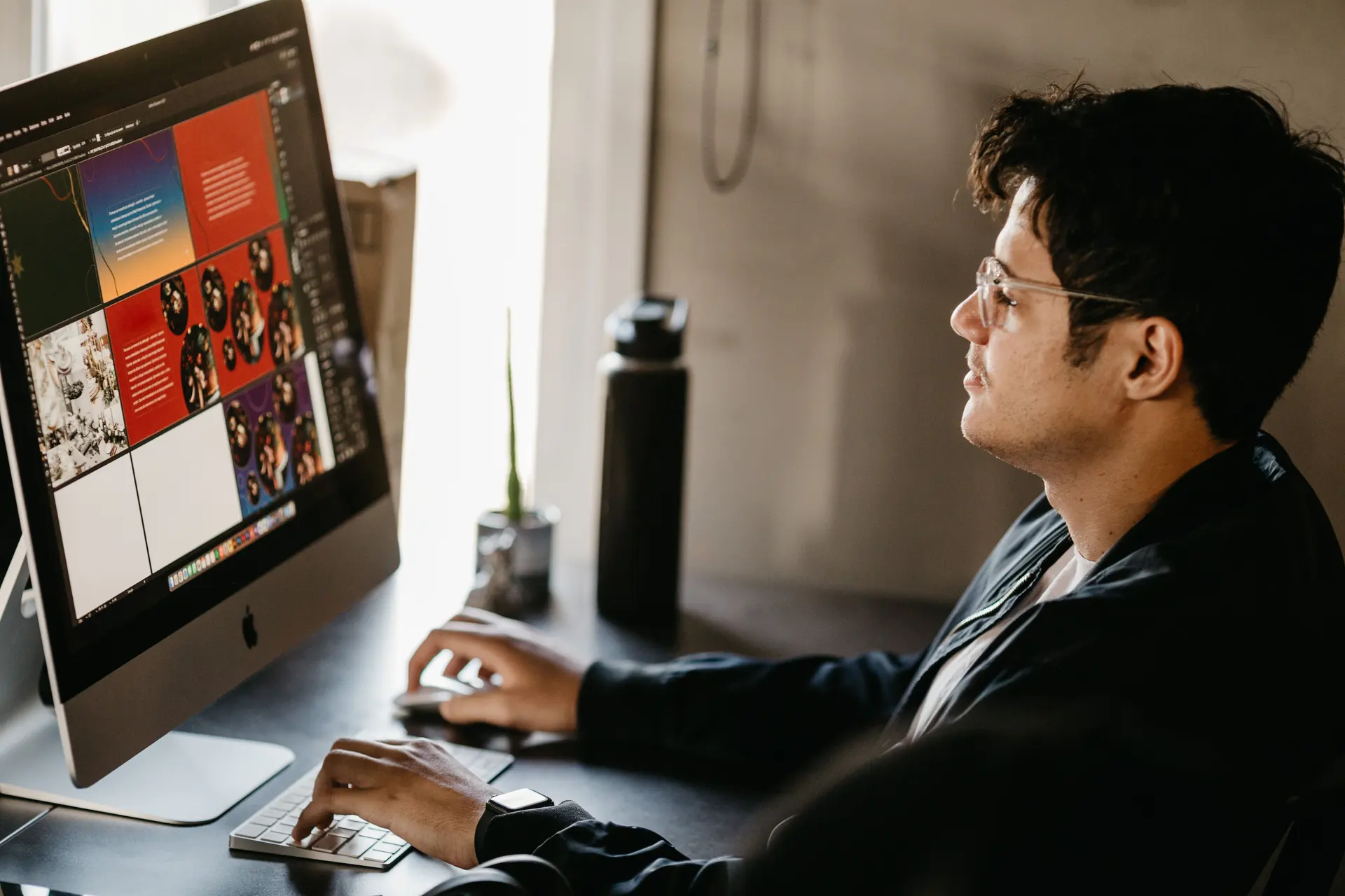 Designer trabalhando em frente a um computador com ferramenta de criação aberta na tela