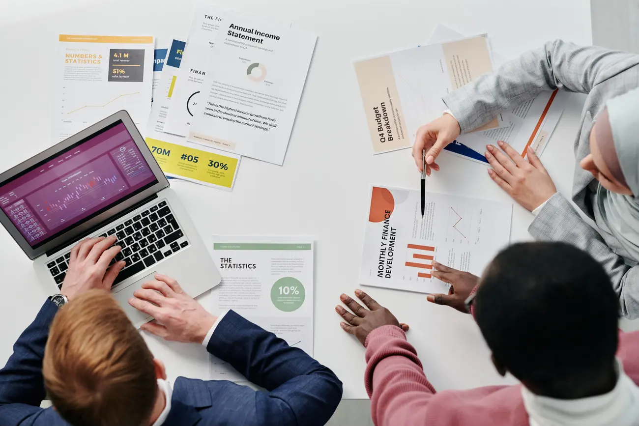 Equipe de marketing analisando relatórios de desempenho e gráficos financeiros sobre a mesa