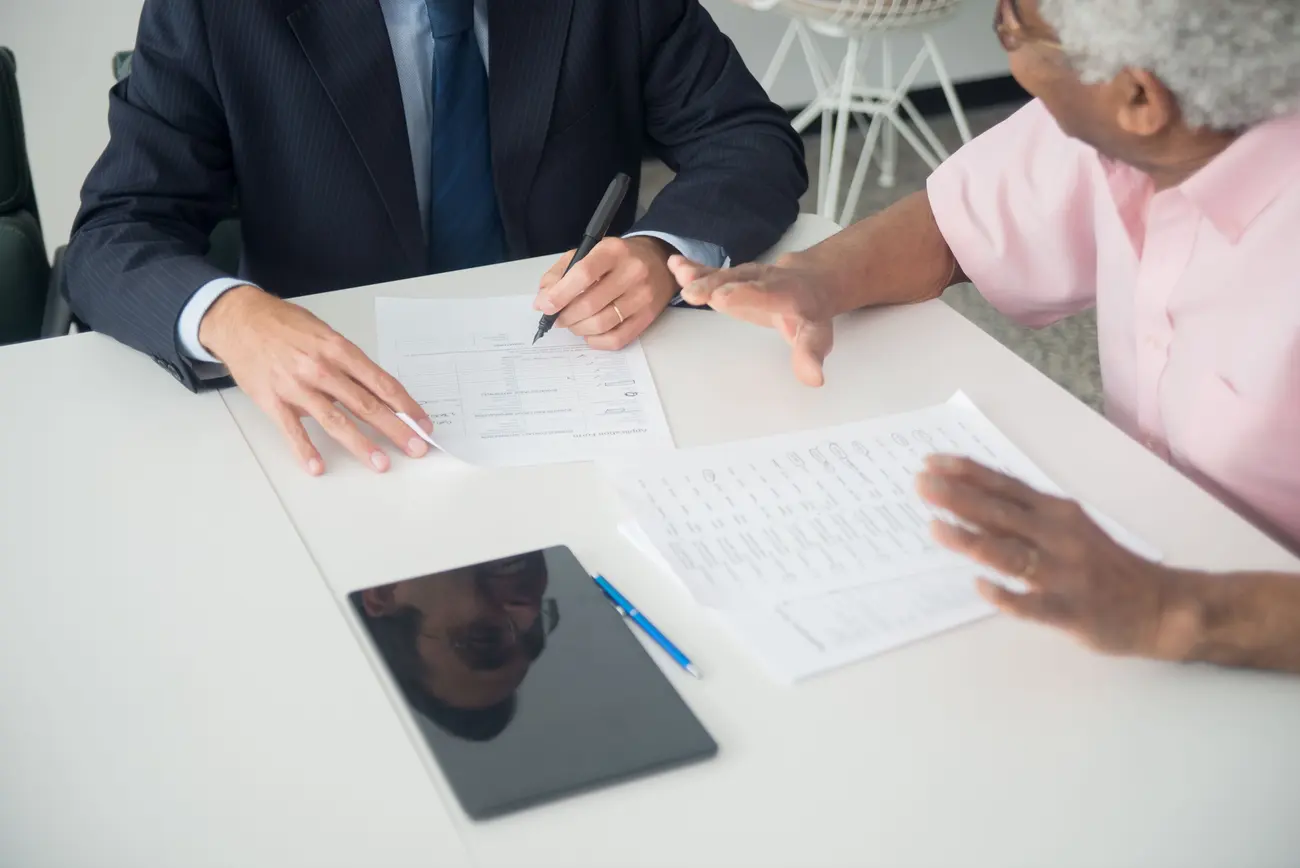 Consultor e cliente revisando documentos juntos durante uma reunião de atendimento