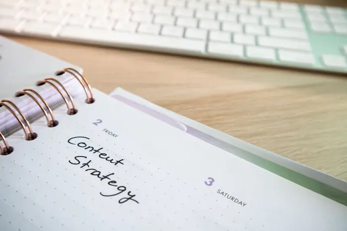 Planner de conteúdo aberto sobre a mesa com a anotação Content Strategy escrita à mão