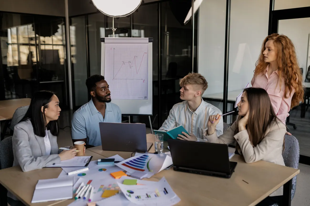Equipe de marketing reunida analisando gráficos de campanha em um quadro
