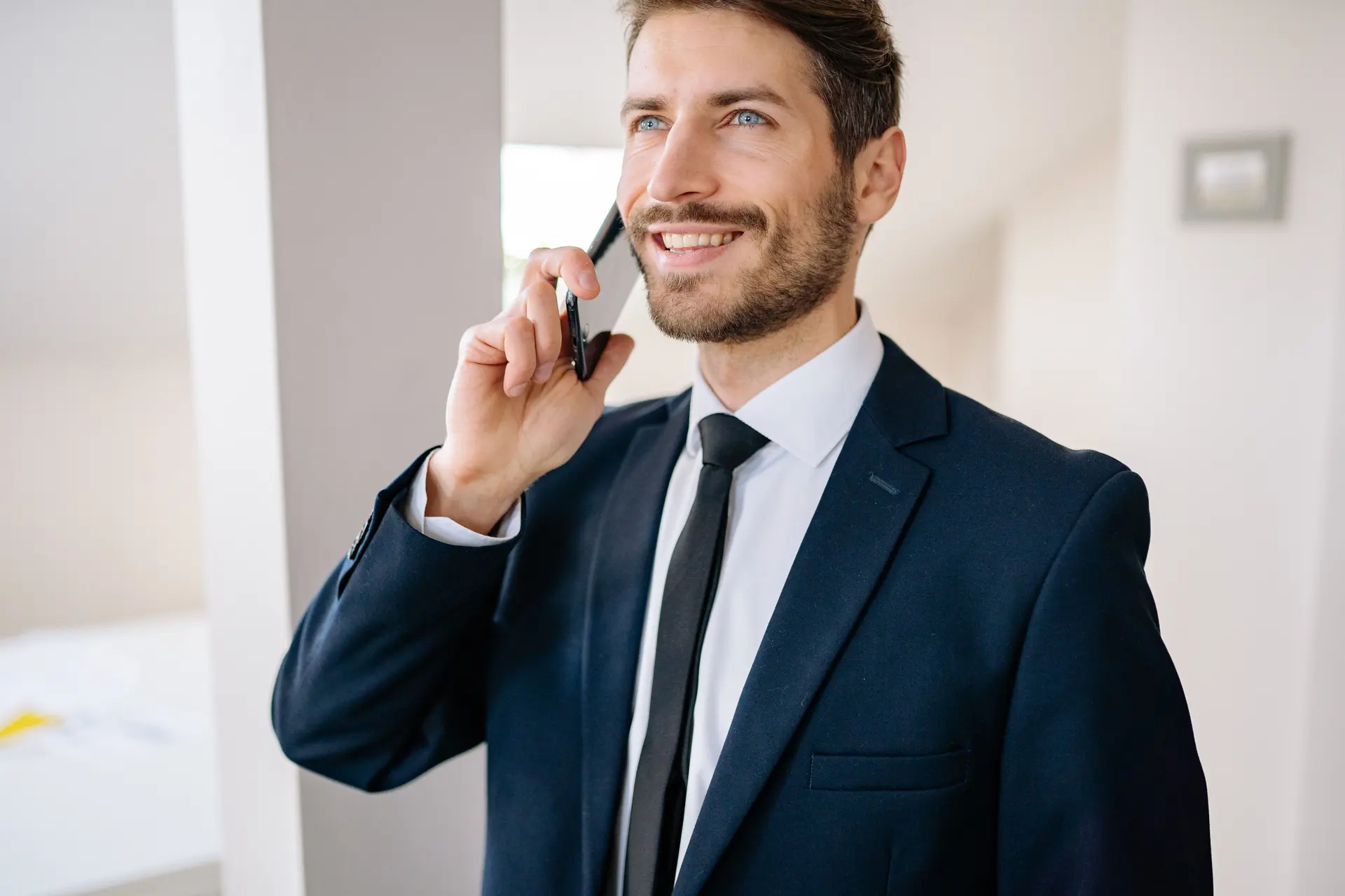 Homem de terno sorrindo ao telefone durante uma negociação de venda