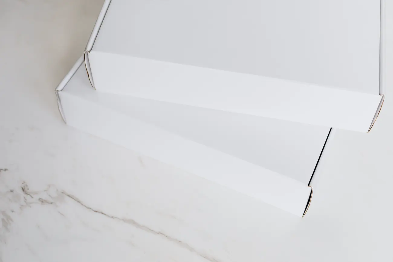 Caixas de encomenda brancas prontas para envio sobre uma bancada de mármore