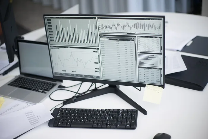 Monitor mostrando painel de gráficos e dados sobre uma mesa de escritório