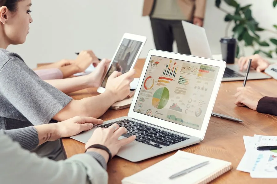 Equipe em reunião comparando gráficos de resultado em dois notebooks