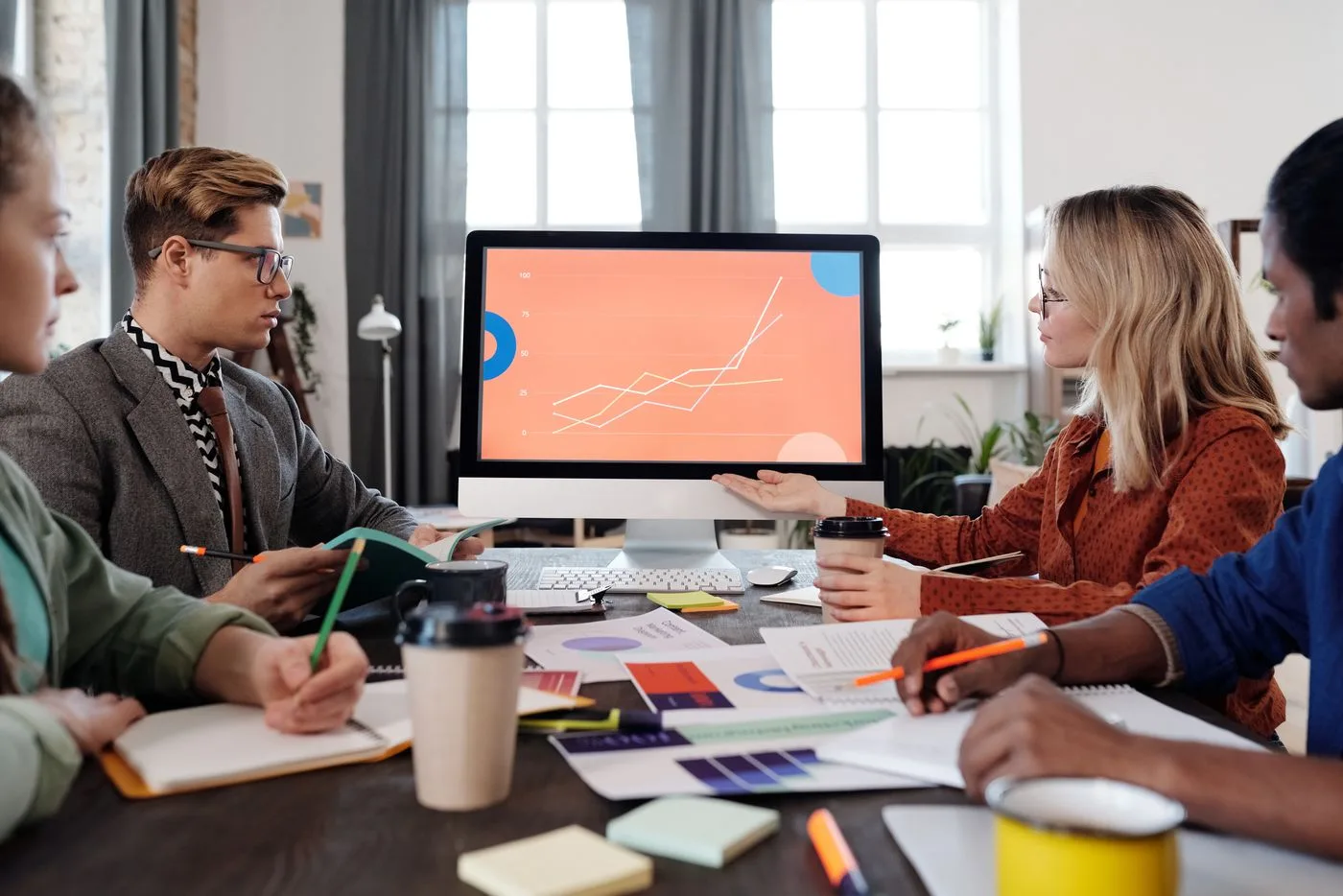Equipe reunida olhando um gráfico de desempenho em um monitor grande