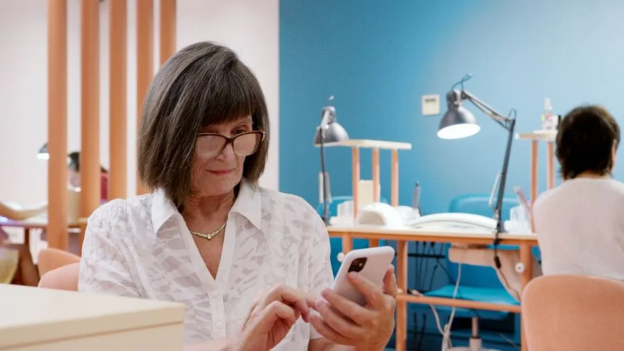 Dona de salão de beleza sentada respondendo mensagens no celular